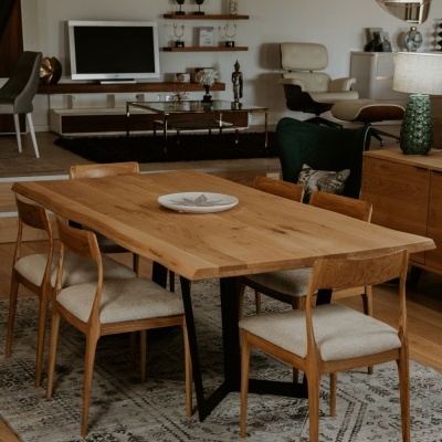 Mesa de jantar de madeira clara com cadeiras estofadas e tapete geométrico