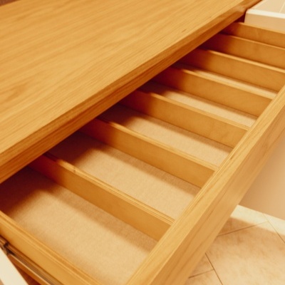 Gaveta de madeira clara com divisórias internas, móvel de cozinha ao lado de bancada branca