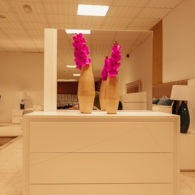 Cómoda branca com espelho e vasos com flores rosas