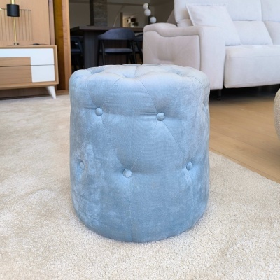 Pufe redondo azul de veludo com botões capitonê num tapete creme