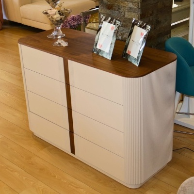 Cômoda branca com tampo em madeira castanha e detalhes verticais, em sala com chão de madeira clara