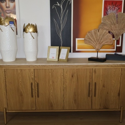 Aparador de madeira com decoração de vasos, porta-retratos e esculturas de folhas