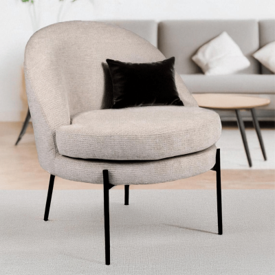 Cadeirão cinza claro com almofada preta e pés negros em sala com sofá e mesa oval.