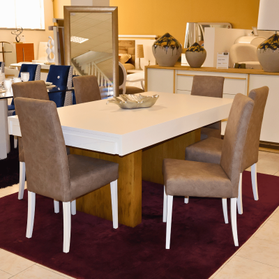 Mesa de jantar branca com base de madeira e seis cadeiras castanhas, em tapete roxo, em loja de móveis.