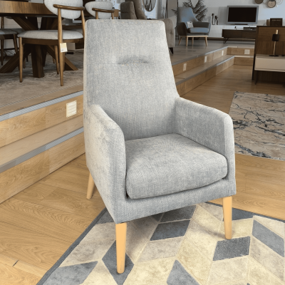 cadeira estofada cinzento claro com pernas de madeira sobre tapete geométrico