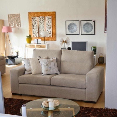 Sofá bege de tecido com almofadas decorativas numa sala decorada