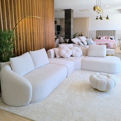 Sofá modular cinza claro com almofadas e pufe em sala moderna