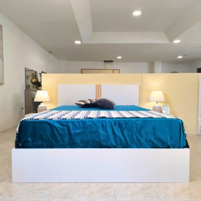 Cama branca com roupa azul e luminárias de mesa num quarto moderno
