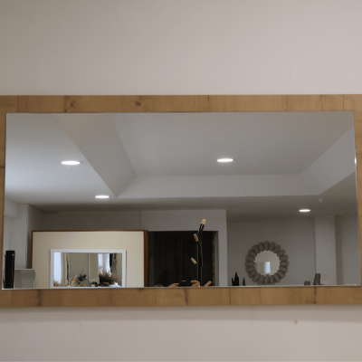 Espelho retangular com moldura de madeira clara numa parede branca