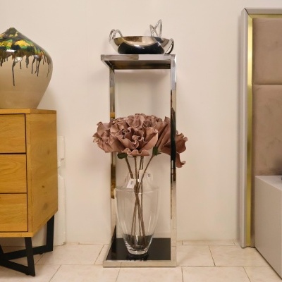 Arranjo de flores artificiais em jarra de vidro em estrutura metálica prateada junto a móveis