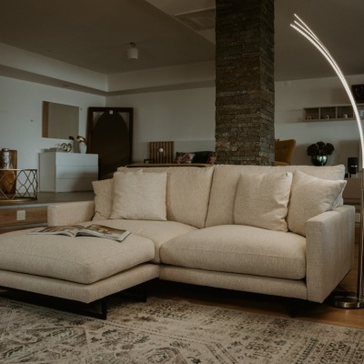 Sofá moderno bege claro com chaise longue em sala ampla com tapete e candeeiro