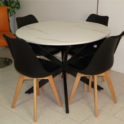 Mesa redonda branca marmoreada com quatro cadeiras pretas com pernas de madeira