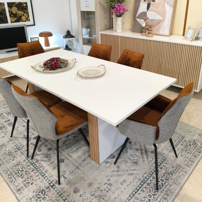 Mesa de jantar branca com seis cadeiras castanhas e cinzentas sobre tapete cinzento com padrão