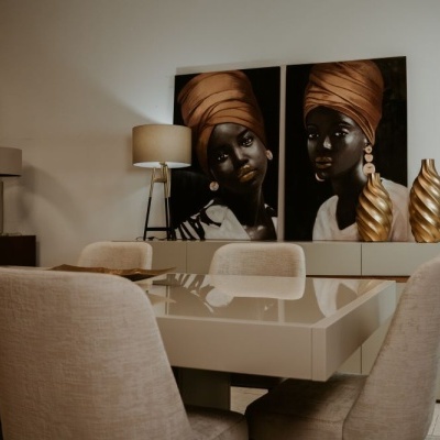 Mesa de jantar branca com cadeiras beges e decoração artística em fundo branco