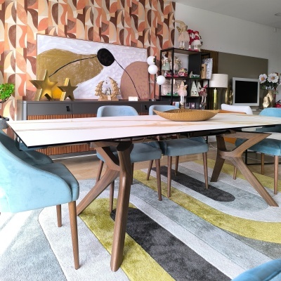 Mesa de jantar com tampo branco e pernas de madeira com seis cadeiras azuis em sala decorada