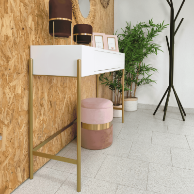 Mesa branca com estrutura dourada, banco rosa, plantas em vasos e cabideiro preto