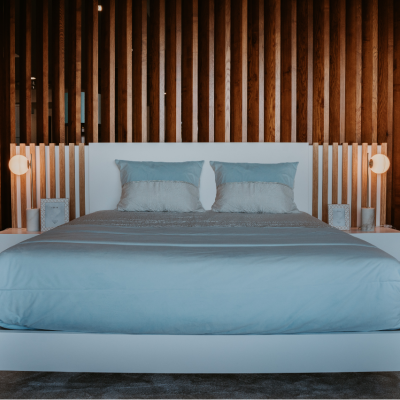 Cama de casal moderna com roupa de cama azul claro e cabeceira de madeira