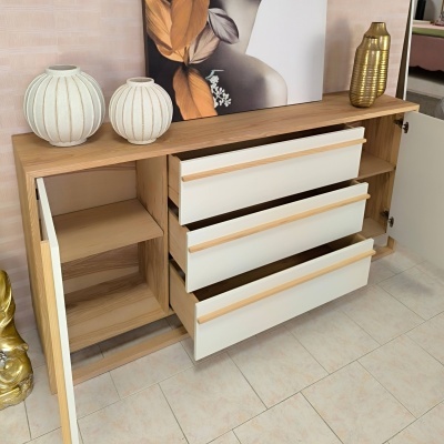 Móvel de madeira clara com gavetas brancas abertas e vasos decorativos em cima