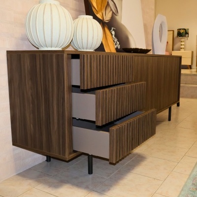 Aparador moderno em madeira castanha com gavetas abertas e peças decorativas brancas em cima.