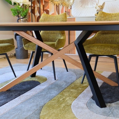 mesa de jantar em madeira e metal com cadeiras amarelas e tapete geométrico