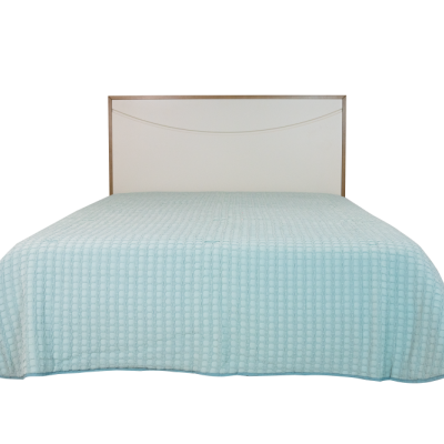 Cama com colcha azul clara e cabeceira branca