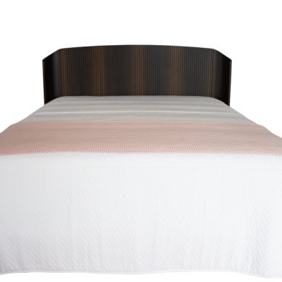 Cama com cabeceira escura, lençol branco e manta cor-de-rosa clara