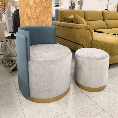 poltrona azul e cinza com pufe cinza com base dourada em loja de móveis