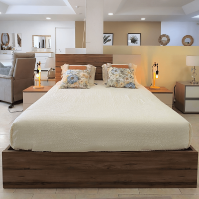 Cama de casal com almofadas floridas e mesas de cabeceira com candeeiros laranja