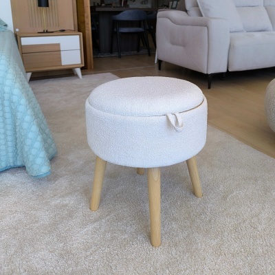 Banco circular branco em tecido bouclé com pernas de madeira clara numa sala com tapete bege e móveis