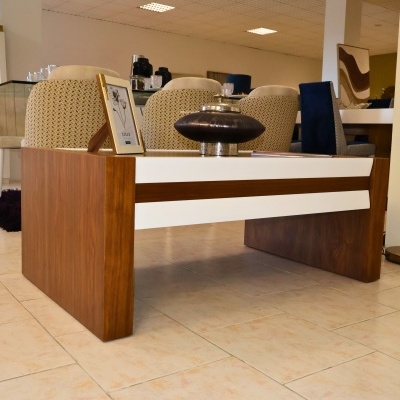 Mesa de centro de madeira com detalhes brancos, vaso de cerâmica e moldura dourada