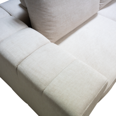 Sofá bege claro de tecido com costuras em quadrados no braço e almofadão atrás
