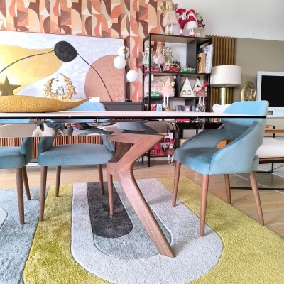 Mesa de jantar com tampo espelhado e cadeiras azuis em ambiente moderno e colorido.