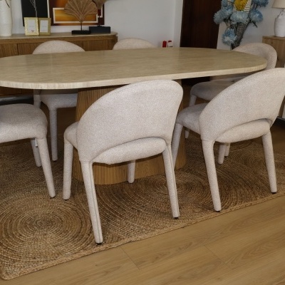 Mesa de jantar oval em pedra com cadeiras cinzentas em tecido sobre tapete de fibras naturais