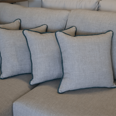 Sofá cinza claro com quatro almofadas cinza de borda verde