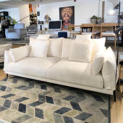 Sofá creme moderno com almofadas sobre tapete geométrico cinza e azul escuro