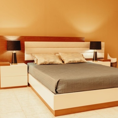 Cama de casal com cabeceira estofada e mesas de cabeceira com candeeiros num quarto com paredes laranja