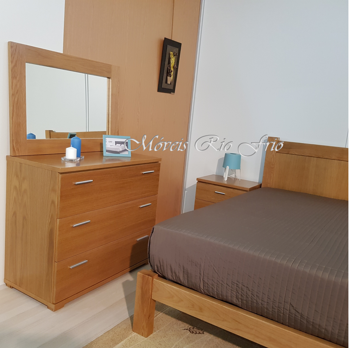 Conjunto de mobiliário de quarto em madeira clara com cómoda, mesa de cabeceira, cama e acessórios azul e cinzento.