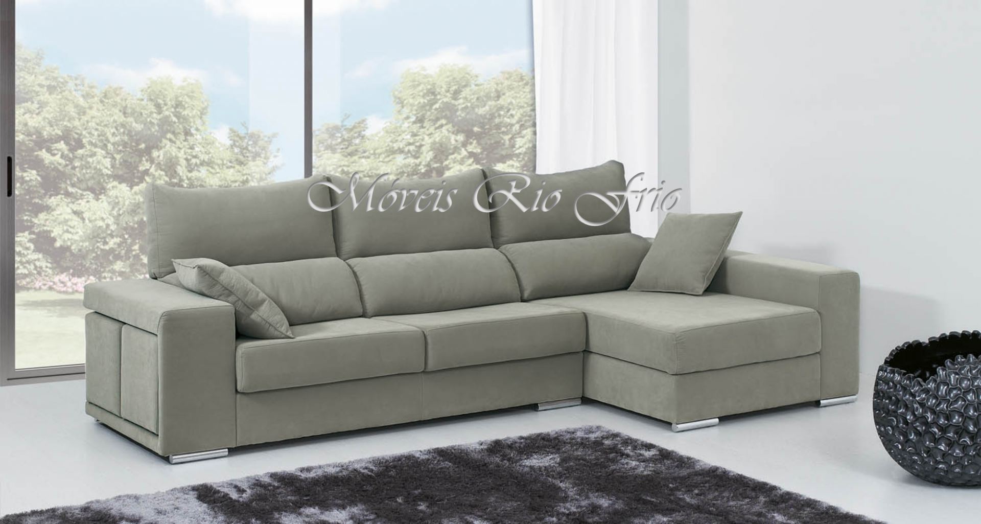 Sofá chaise longue cinzento em ambiente moderno com janelas grandes e tapete escuro.