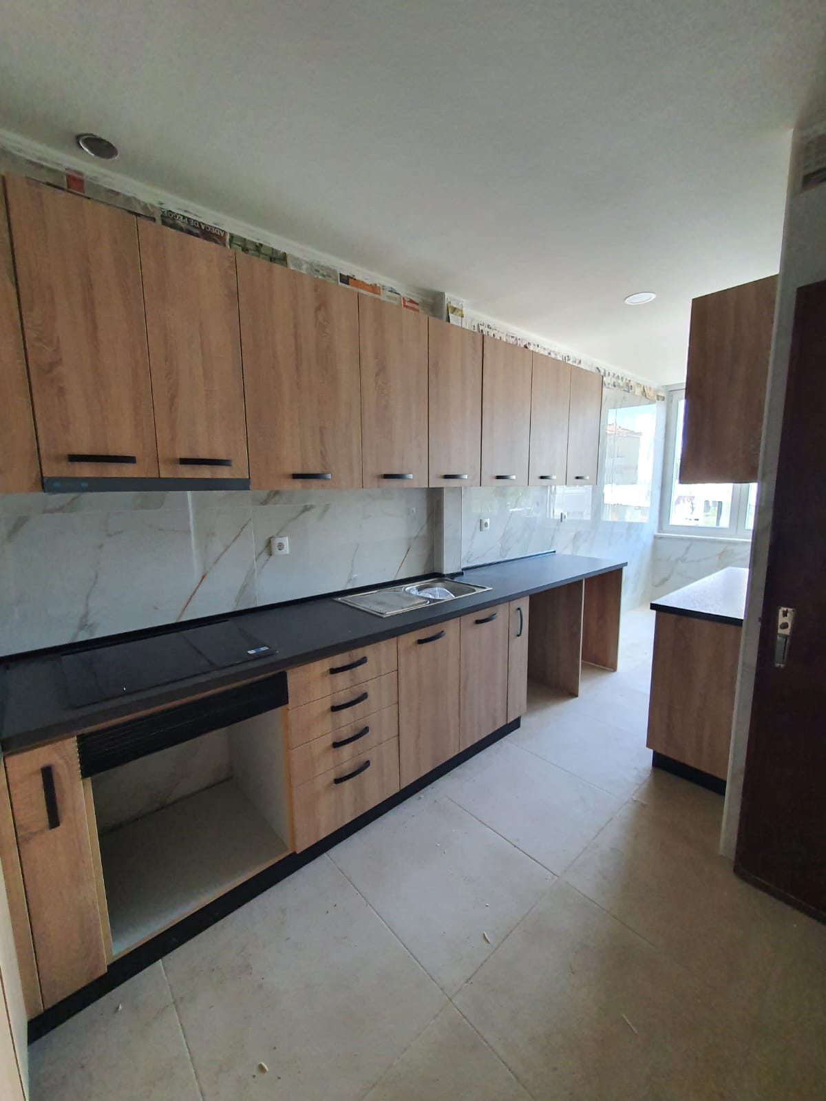 Cozinha com armários de madeira clara e bancada preta