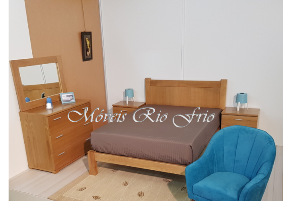 Quarto com cama de madeira, mesas de cabeceira, cómoda com espelho, poltrona azul e tapete bege