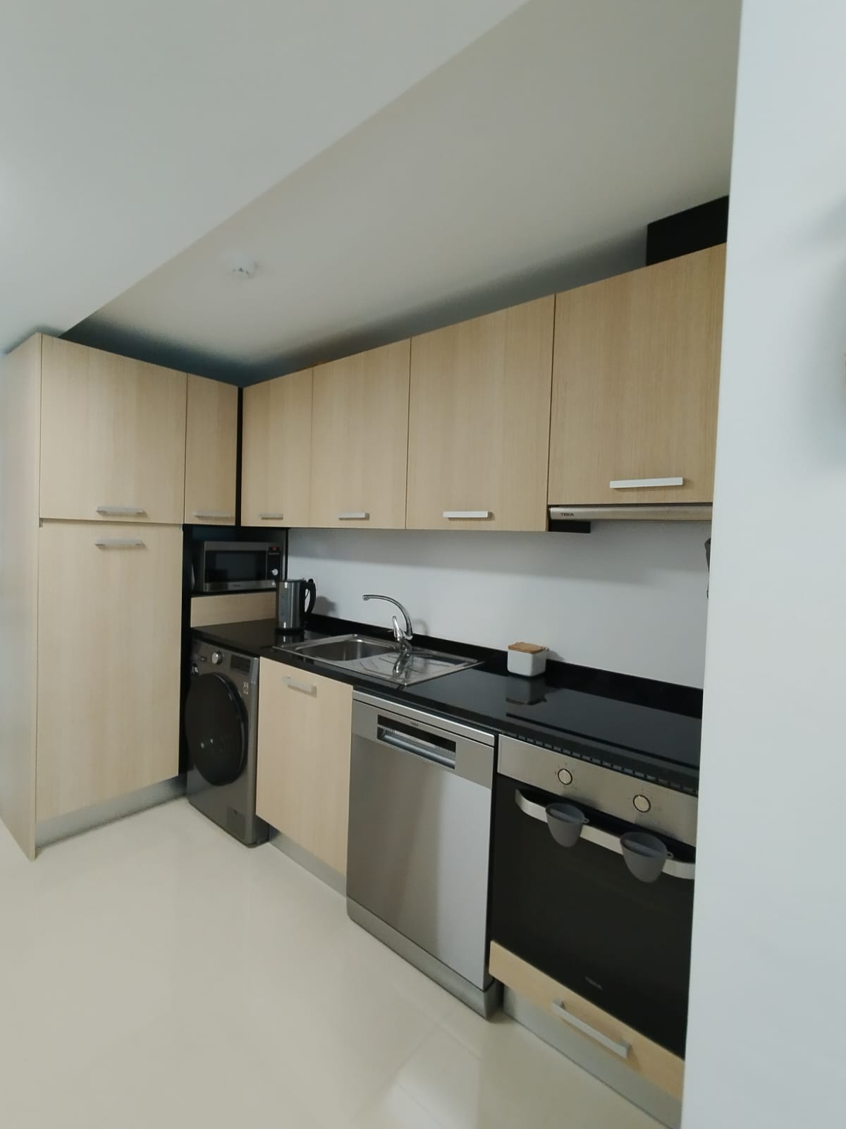 Cozinha moderna com armários de madeira clara e eletrodomésticos em inox e preto