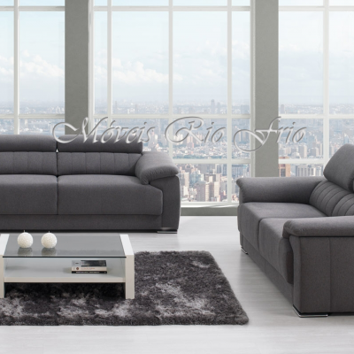 Conjunto de sofás cinzentos com mesa de centro branca e tapete cinzento junto a janelas grandes com vista urbana