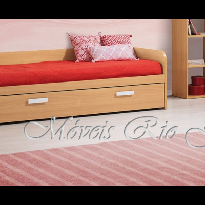 Cama individual em madeira clara com colchão vermelho e almofadas decorativas, gaveta e tapete rosa listrado