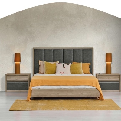 Quarto com cama de madeira e cabeceira cinzenta, roupa de cama laranja e branca, almofadas coloridas, mesas de cabeceira e lâmpadas laranja.