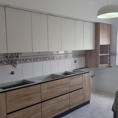 Cozinha com armários em branco e madeira clara e azulejos decorativos