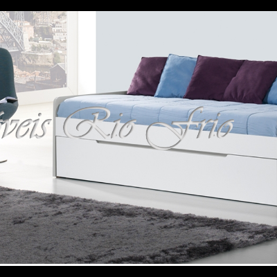 Sofá-cama branco com almofadas azuis e roxas num ambiente minimalista com cadeira azul e tapete cinzento