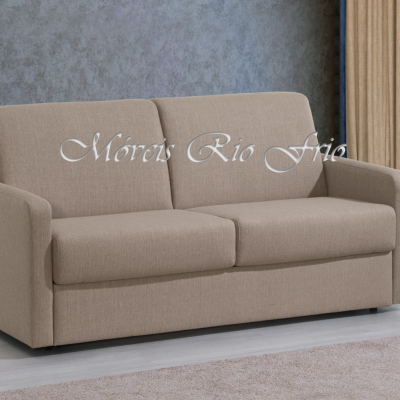 Sofá bege de dois lugares em interior com parede cinzenta e cortinas beige com vista para floresta