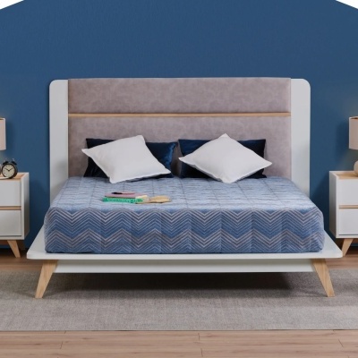 Cama moderna com roupas de cama azuis e brancas, mesas de cabeceira e candeeiros