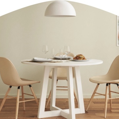 Mesa redonda branca com cadeiras bege e piso de madeira