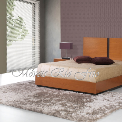 Quarto com cama de madeira, carpete cinza, criado-mudo com candeeiro e cómoda com espelho.